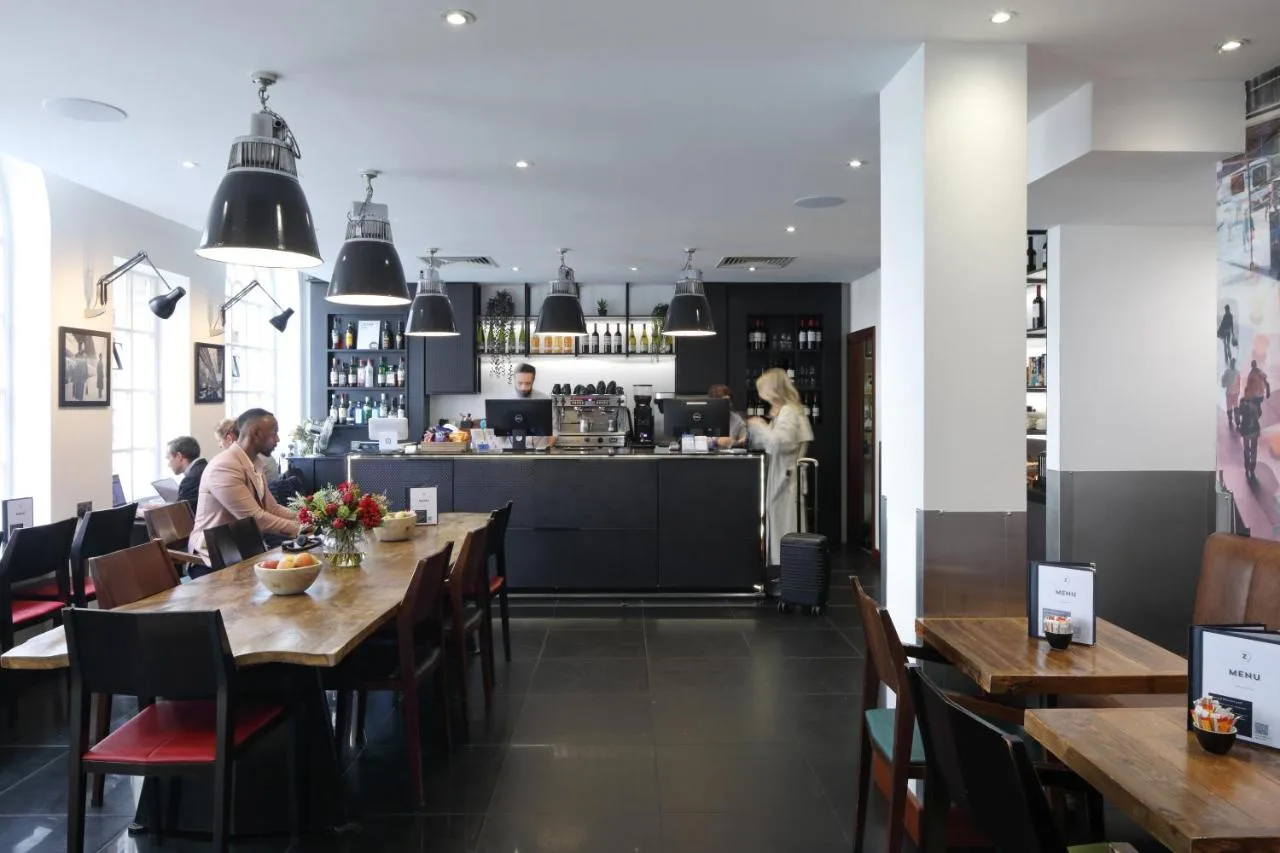 a dining room with people sitting at tables in a restaurant at The Z Hotel Victoria in London
