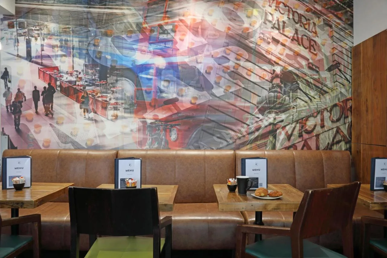 a mural on the wall of a restaurant with tables at The Z Hotel Victoria in London
