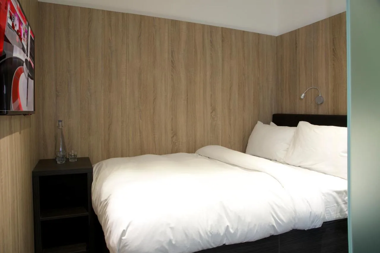 a bed with white sheets and pillows in a hotel room at The Z Hotel Victoria in London